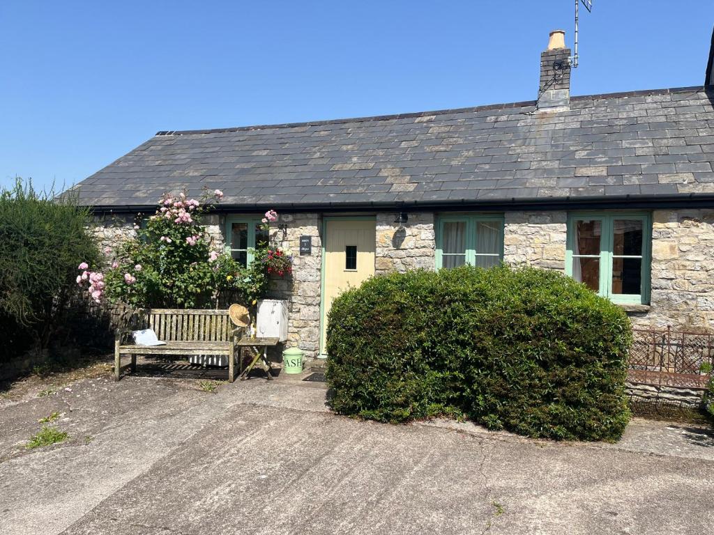 a stone house with a bench in front of it at Wren Cottage in Cowbridge