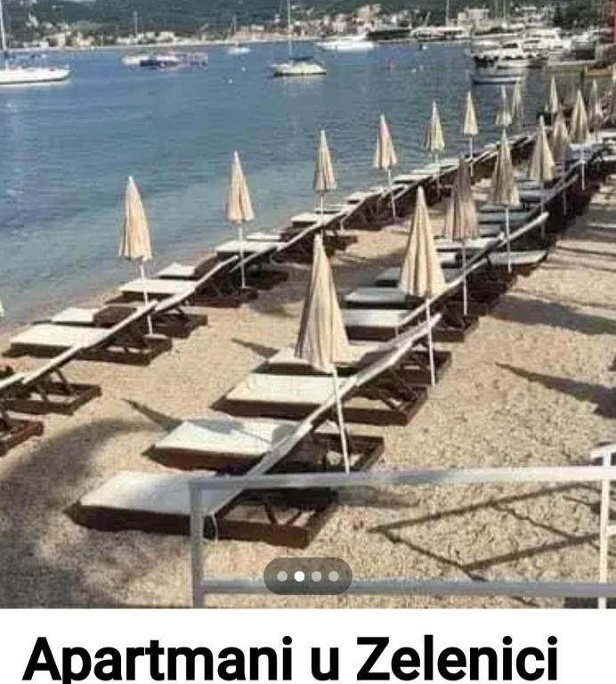 a row of lounge chairs with umbrellas on a beach at Apartment Jelaca in Herceg-Novi