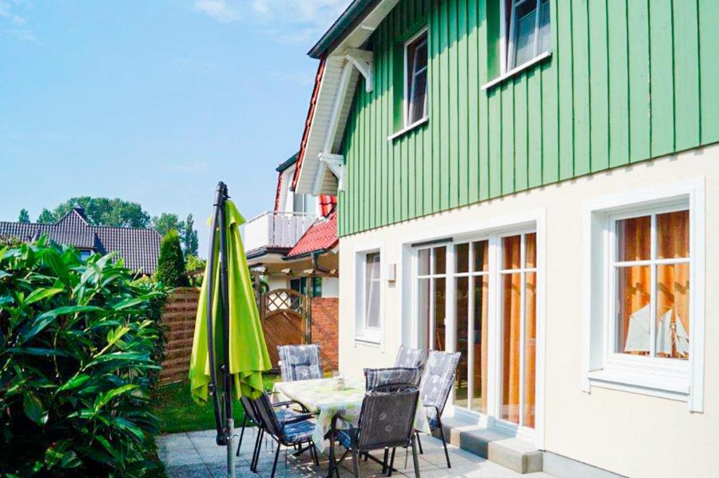 a patio with a table and chairs and a green house at Ferienhaus Katharina in Zingst