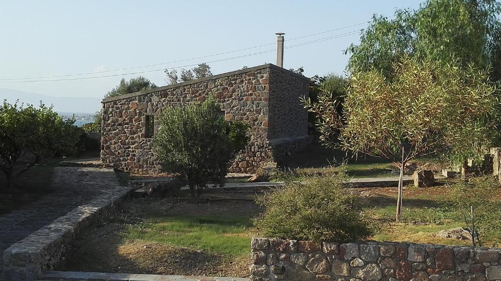 ein Steingebäude mit Bäumen davor in der Unterkunft To Spitaki House in Perdika