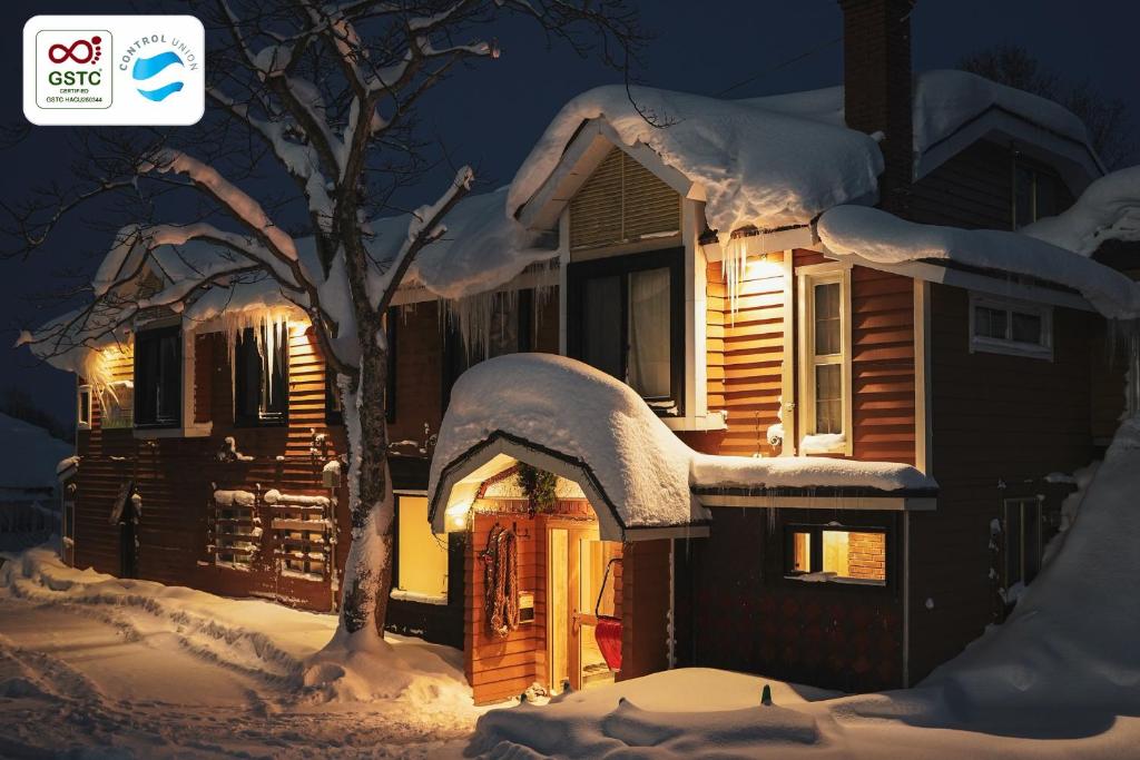 a house covered in snow at night at Country Inn Milky House in Niseko