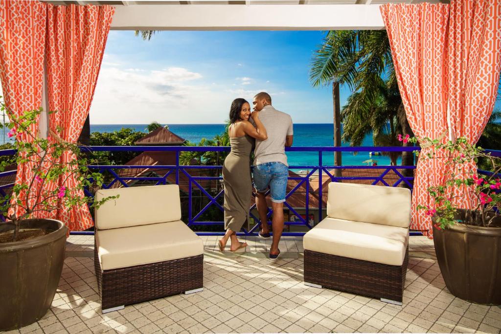 um casal de pé na varanda de um resort em Deja Resort All Inclusive em Montego Bay