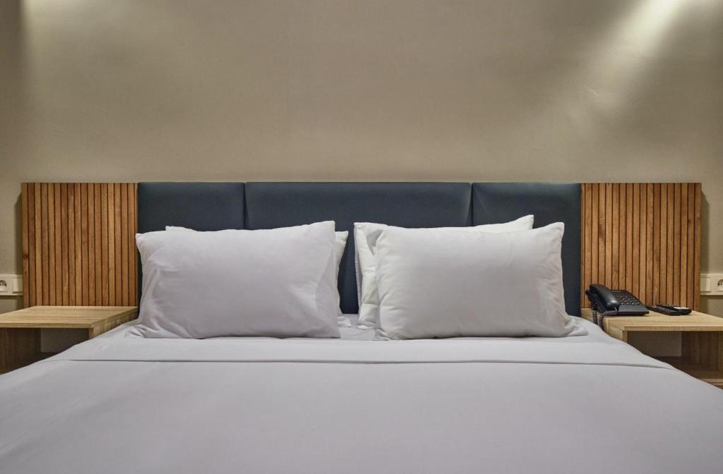 ein Bett mit weißen Kissen und einem blauen Kopfteil in der Unterkunft Sheldon Hotel in Yerevan