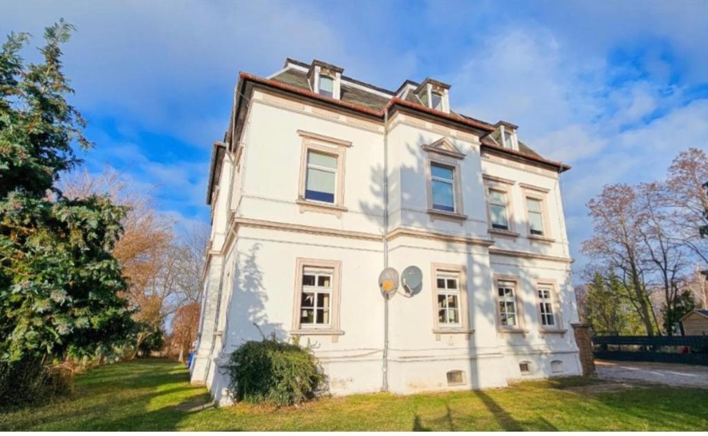 an old white house on a grass field at Zimmervermietung Villa Meuselwitz in Meuselwitz