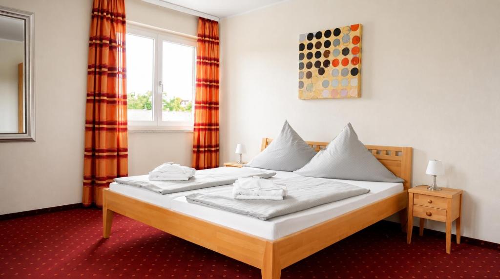 a bedroom with a bed with white sheets and a window at Hotel Leitner in Kaufbeuren
