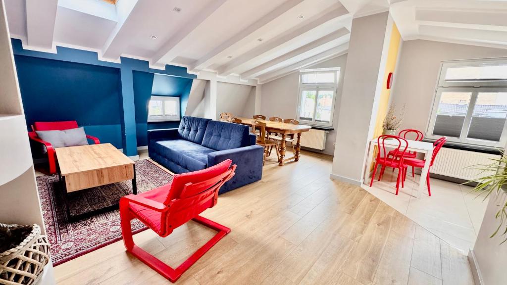 a living room with a blue couch and red chairs at Sopot Przy Plaży in Sopot