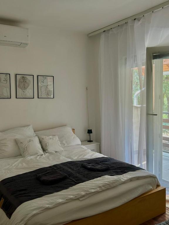 a white bedroom with a large bed with a window at Fehér Villa in Kővágóörs