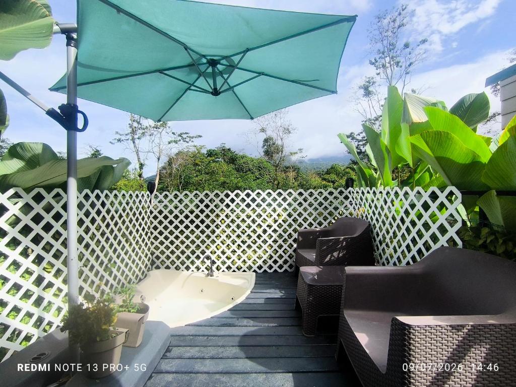 a patio with a blue umbrella and some chairs at Tucan container in Fortuna