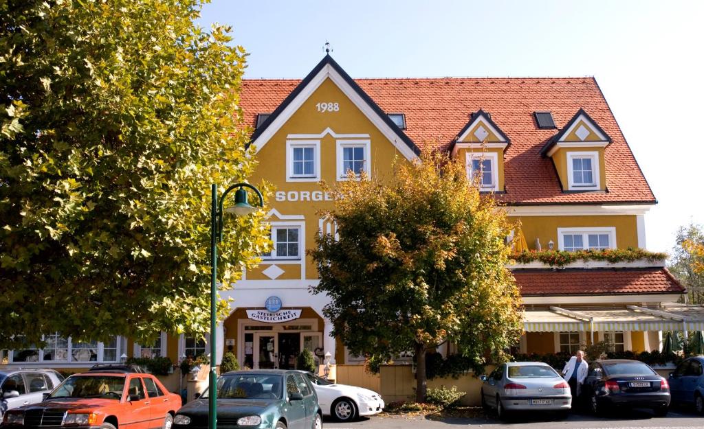 duży żółty budynek z samochodami zaparkowanymi przed nim w obiekcie Sorgerhof w mieście Frauental an der Lassnitz 