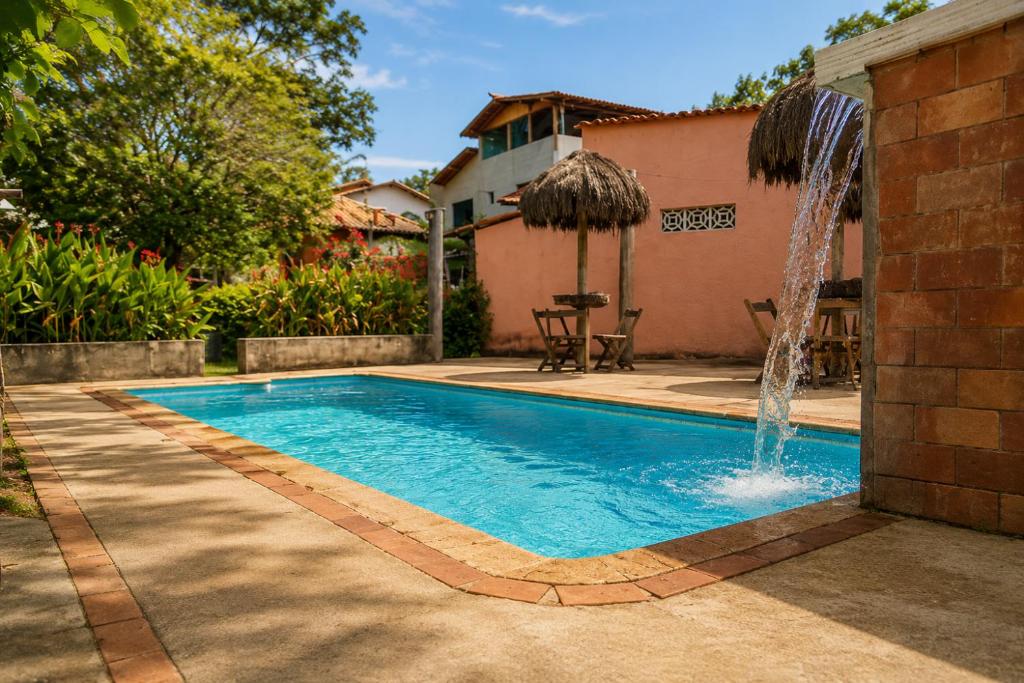 a swimming pool with a fountain in a yard at Pousada Sítio Xodó in Santana do Riacho
