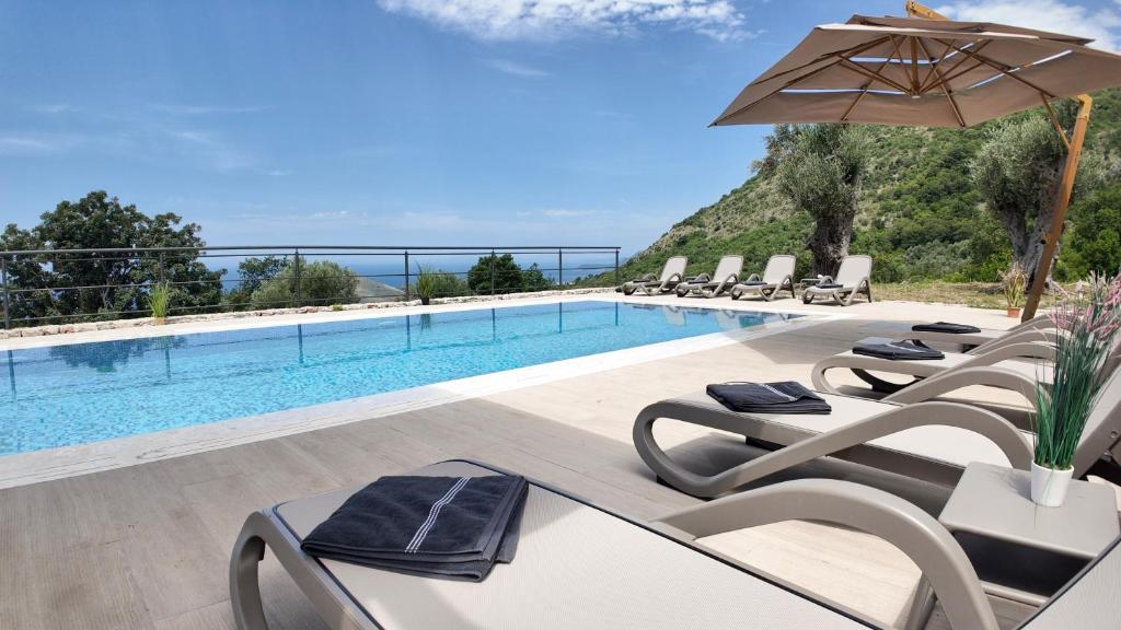 a pool with lounge chairs and an umbrella at Villa Adria Heights in Pečurice