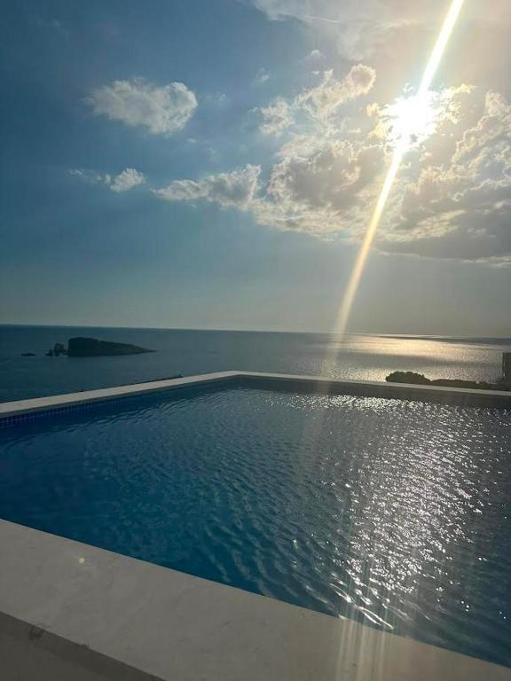 a swimming pool with the sun shining in the sky at ZIS LUX Sea View in Kravlja