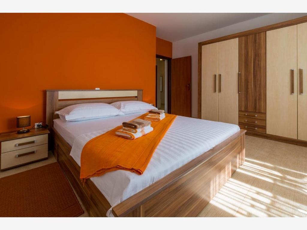 a bedroom with a large bed with an orange wall at Apartment Ivana in Crikvenica