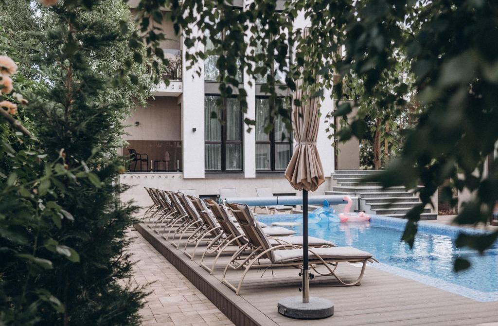 a row of lounge chairs and an umbrella next to a pool at Клубний дім D2 in Chornomorsk