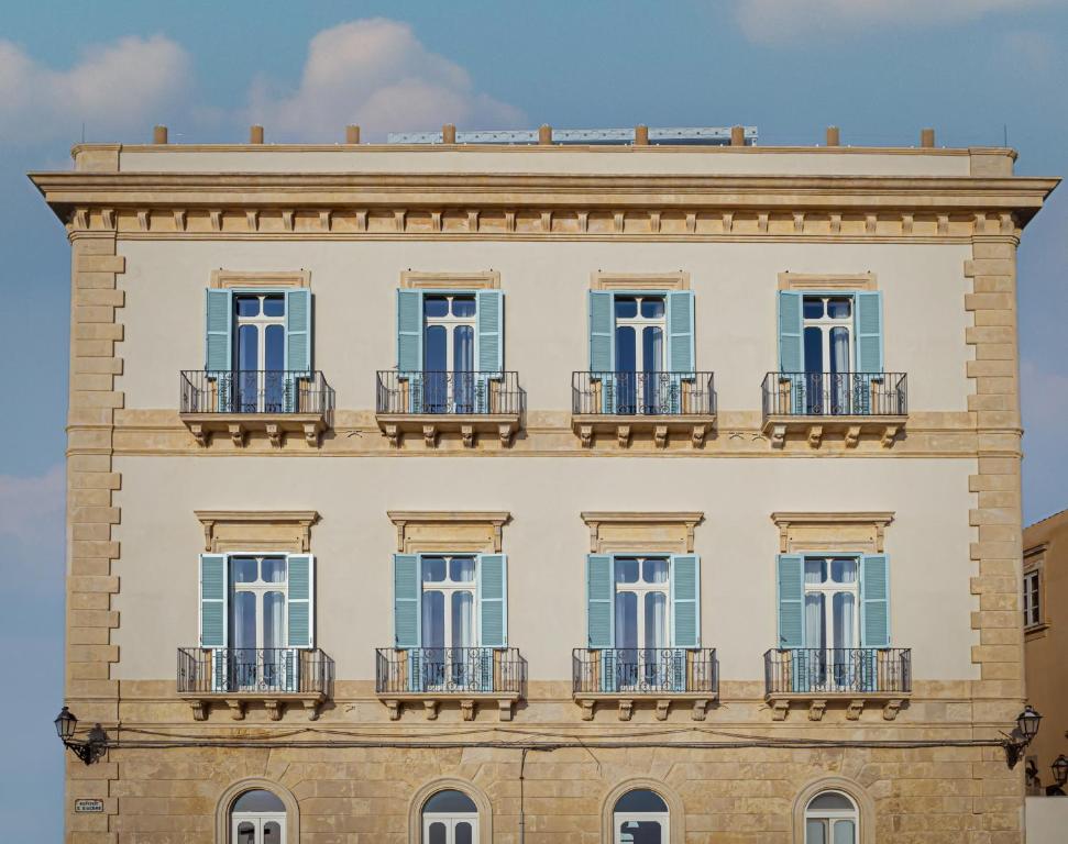 a building with blue doors and balconies on it at EGEO - Ortigia in Syracuse
