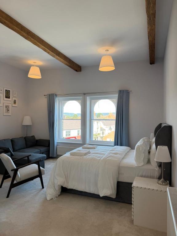 a bedroom with a bed and a couch and windows at Nova Rooms in Thirsk