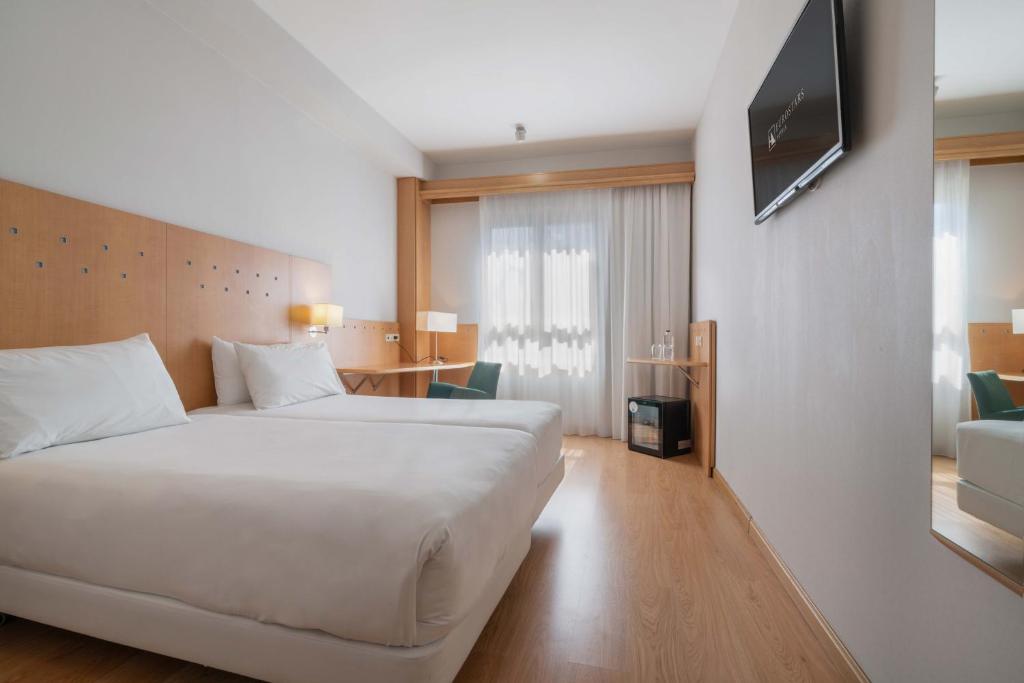 a hotel room with a bed and a television on a wall at Crisol Leganés in Leganés