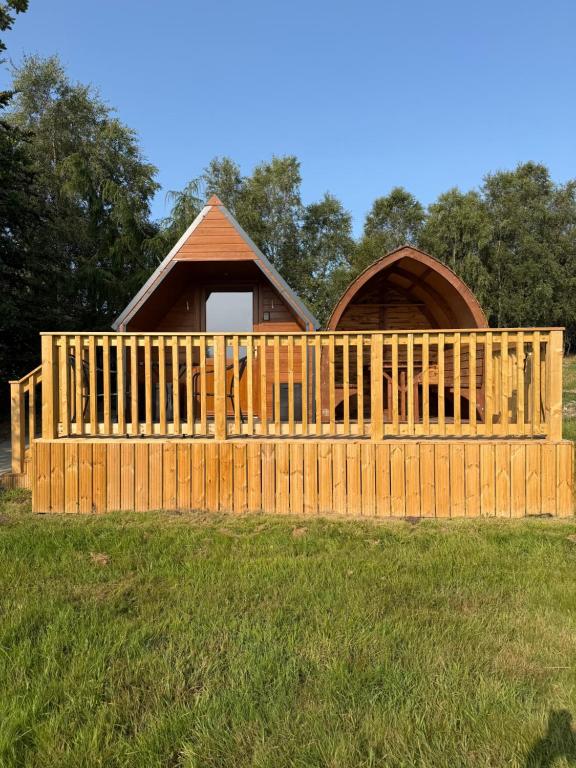 a cabin with a wooden fence in the grass at Meadow View Glamping Hut in Tregaron
