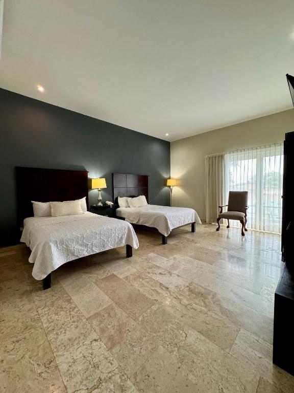 a large bedroom with two beds and a chair at Grann Hotel in Ciudad Valles
