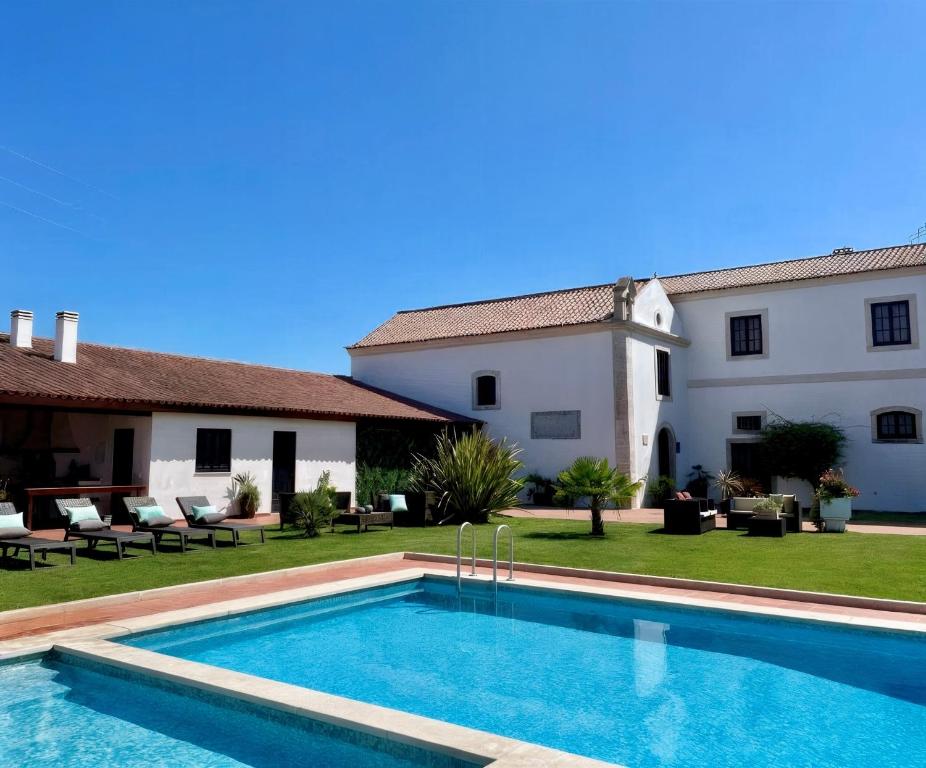 a villa with a swimming pool in front of a house at Quinta da Atela in Alpiarça