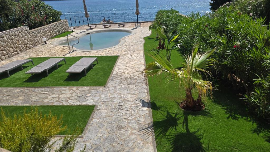 a swimming pool with benches and the ocean in the background at OlivaBeachHouse - Direct Waterfront & Mooring in Barbat na Rabu