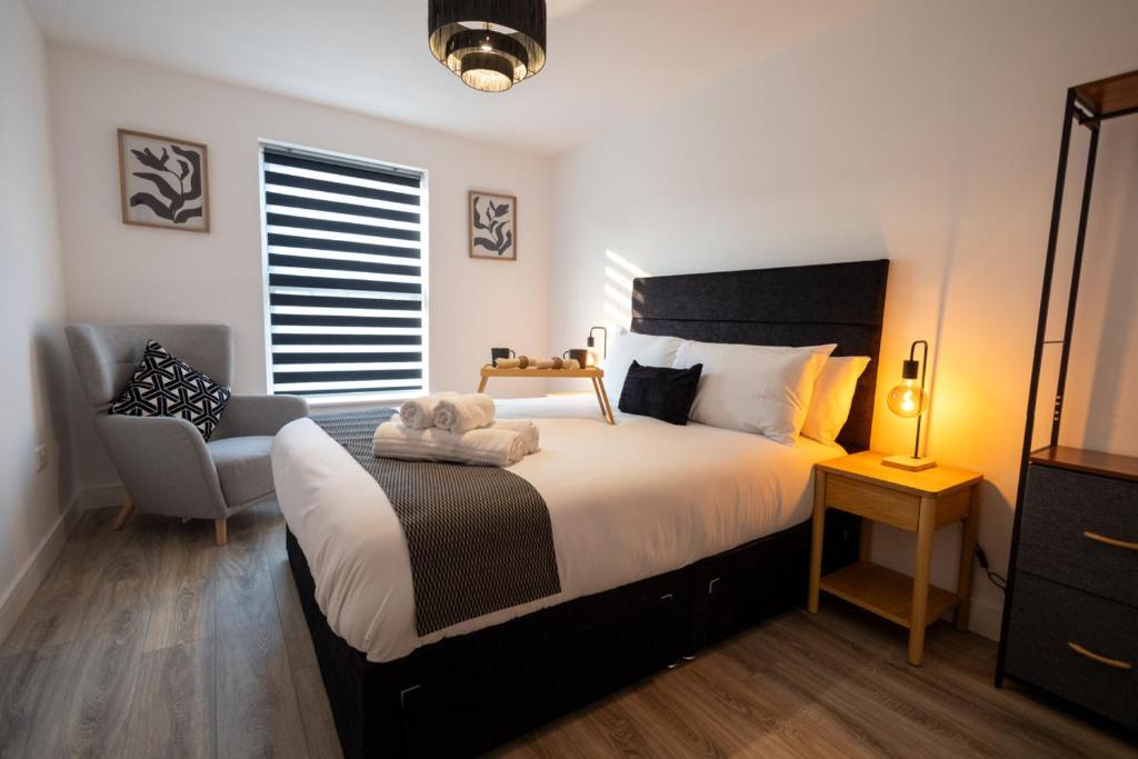 a bedroom with a large bed and a chair at Watford 2-Bed Oasis - 20-min to London - Central in Watford