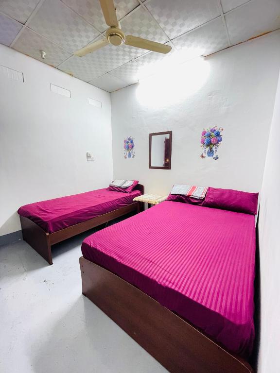 two beds in a room with pink sheets at Lathu - zen Stay Hotal in Trincomalee