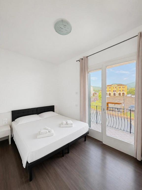 a white bedroom with a bed and a large window at Locanda Al Sole in Vo Euganeo