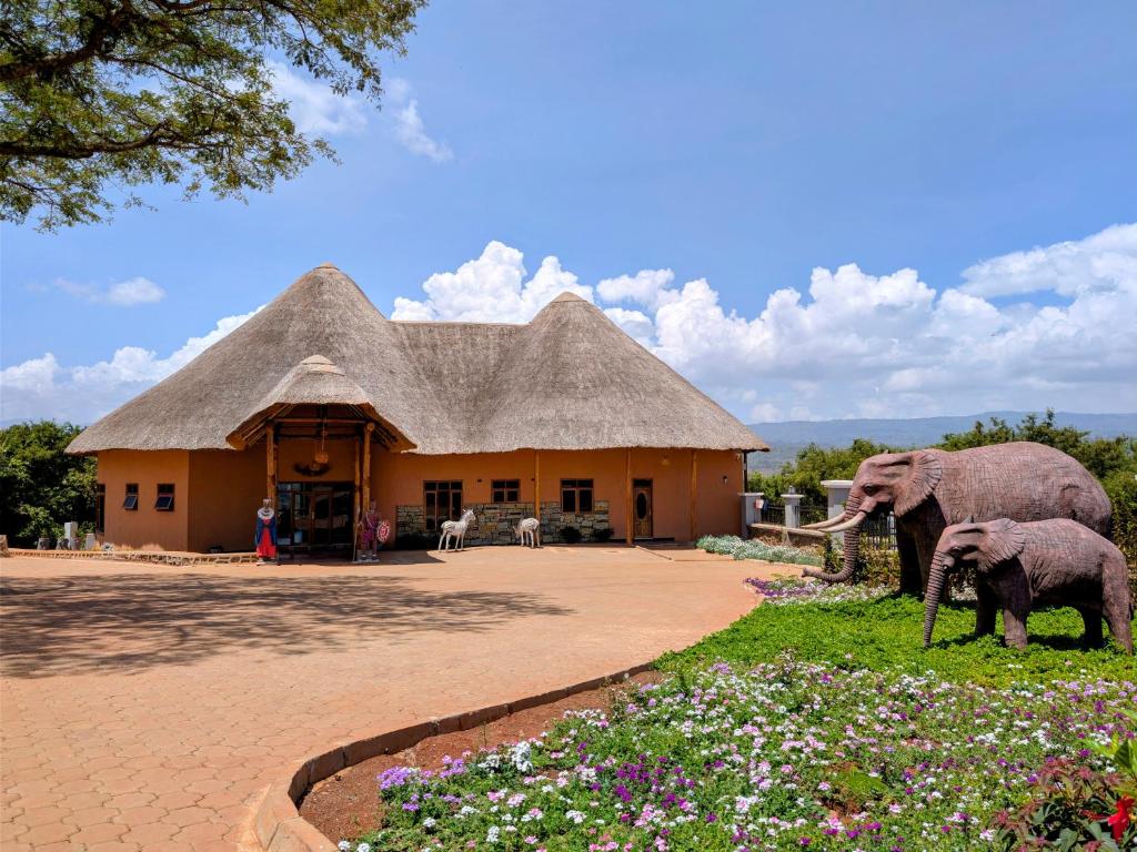 two elephants standing in front of a building with flowers at Maasai ecoLodge in Karatu