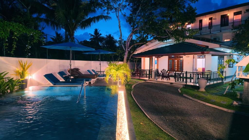 a swimming pool with chairs and umbrellas next to a building at Sea Bloom Villa in Kamburugamuwa