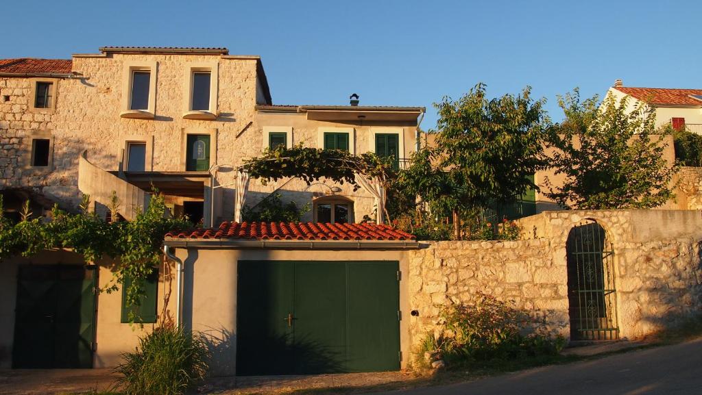 un bâtiment avec un garage vert à côté d'un mur en pierre dans l'établissement Holiday Home Oliva, à Bilice