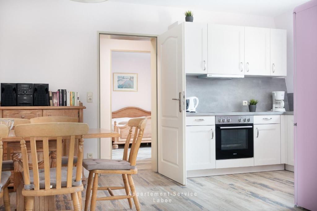a kitchen with white cabinets and a table and chairs at Wiesenweg W10 in Laboe