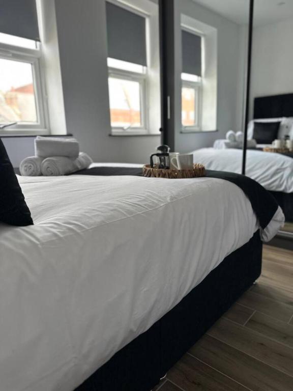 a bedroom with two beds with white sheets and windows at Modern Borehamwood Flat - 2 Min Walk to Station in Borehamwood