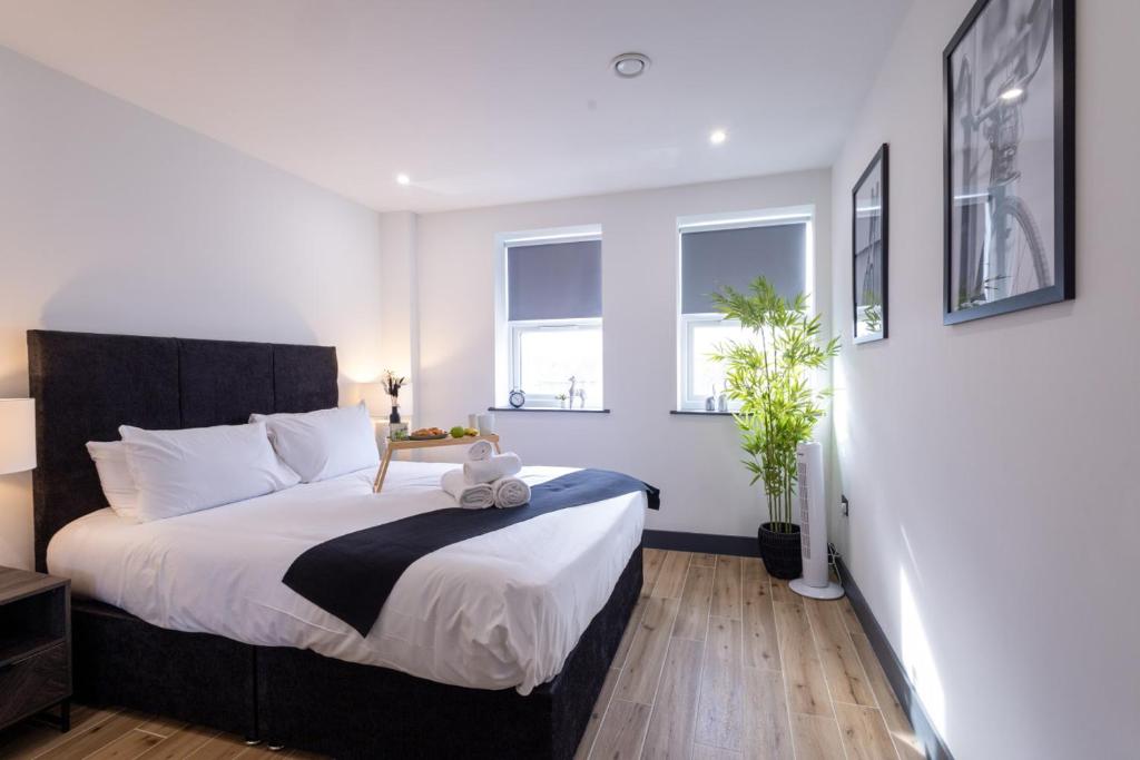 a bedroom with a large bed and two windows at Brand-New Borehamwood 1-Bed, 1-Bath Flat in Borehamwood