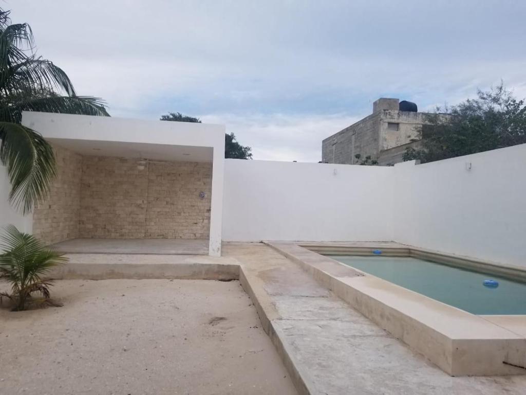 a swimming pool on the side of a white wall at Minimalist house with pool and patio in Chicxulub