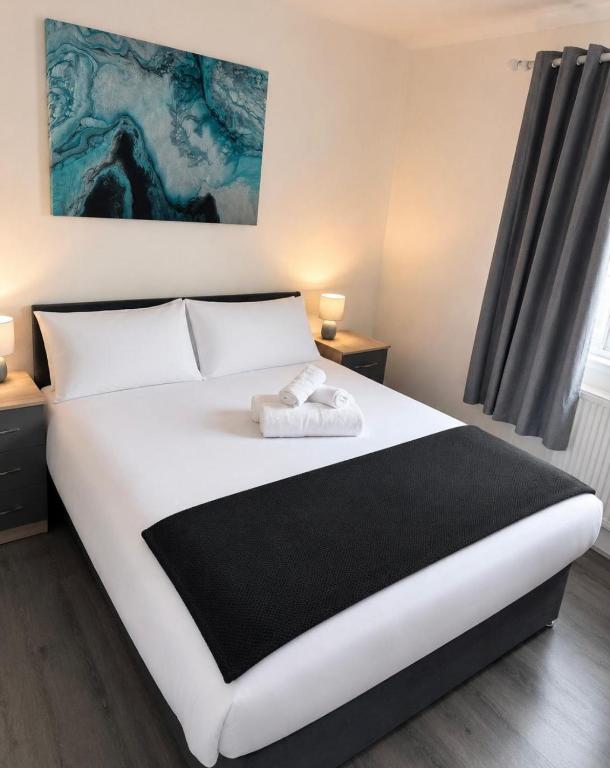 a bedroom with a large white bed with a black blanket at Large 4-Bedrooms Corporate Flat, Free Parking - Amazing Location in Leavesden Green