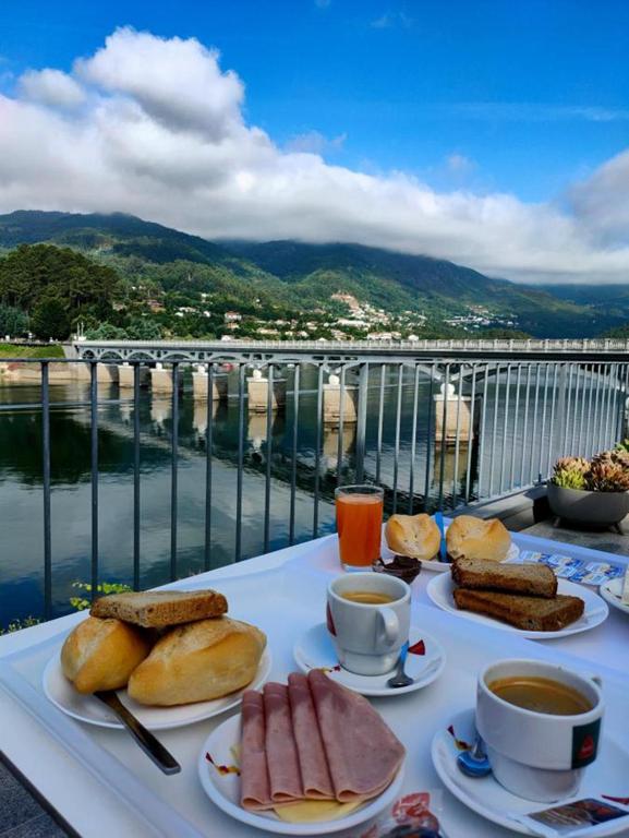 a table with plates of food and coffee on a balcony at Beira Rio do Gerês in Geres