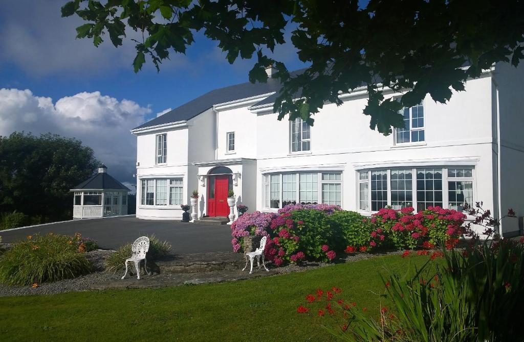 una casa bianca con due sedie in un cortile di Carrabaun House a Westport