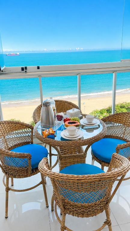 a table with chairs and a tea set on the beach at Frente mar na praia de Itaparica! in Vila Velha