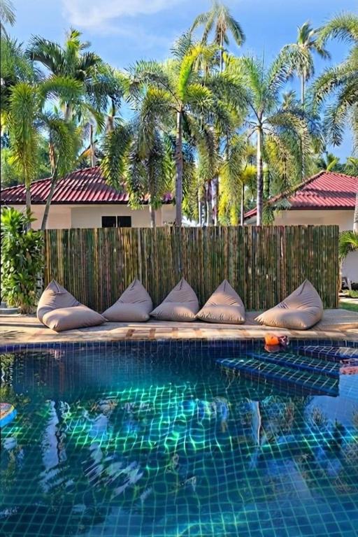 a swimming pool with pillows next to a wooden fence at Baan Sawang hidden in tropical calm in Ban Tai