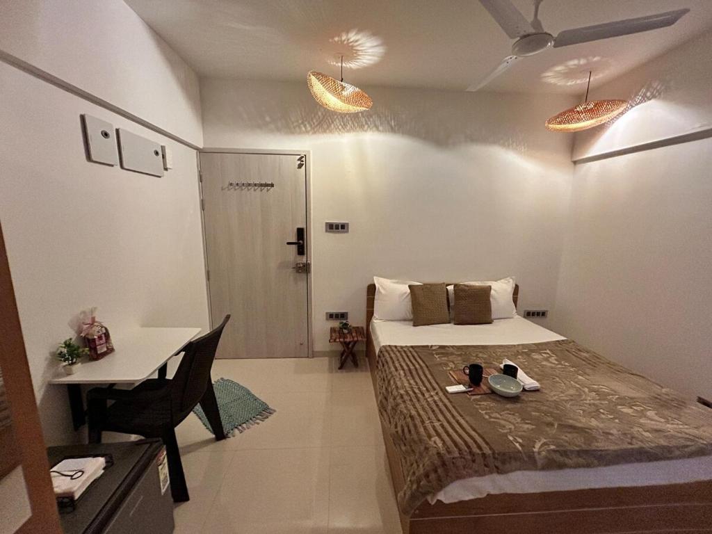 a small room with a bed and a desk and a table at Zen LuxStudio in Pune