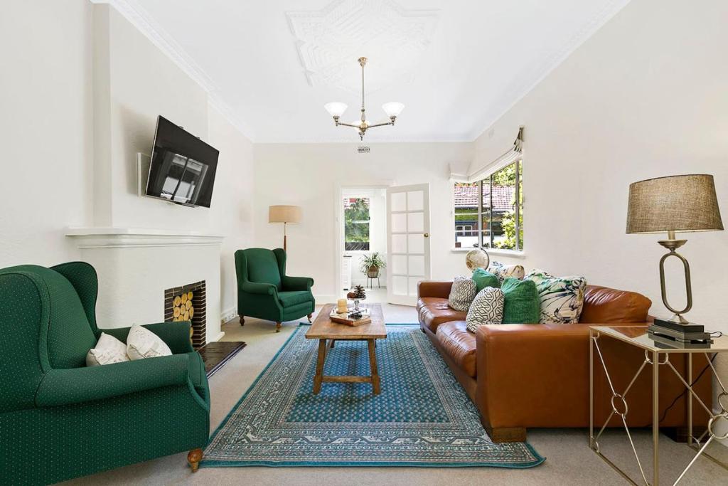 a living room with a brown couch and green chairs at Stylish Apartment, Malvern East in Melbourne