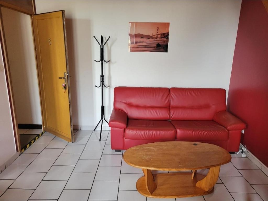 a living room with a red couch and a coffee table at Le Duplex Bordeaux in Saint-Jean-dʼAngély