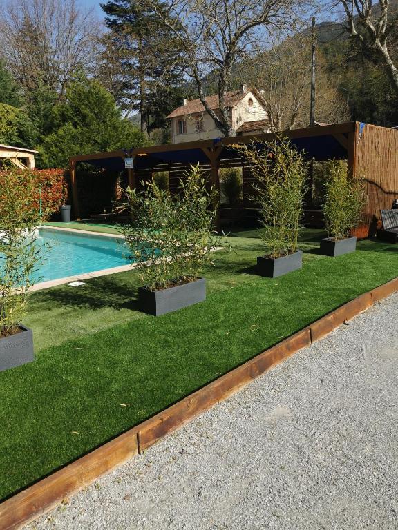 a backyard with a swimming pool with potted plants at Hôtel Les Alizés in Puget-Théniers