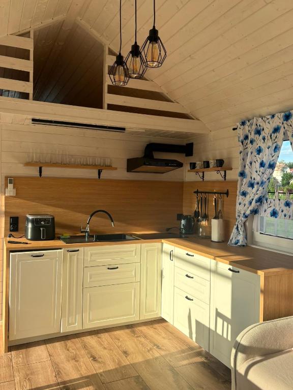 a kitchen with white cabinets and a sink at Domek Chabrowy Gowidlino in Gowidlino