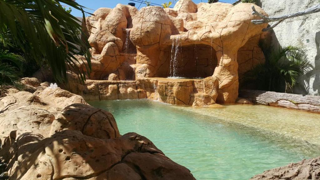 a swimming pool with a waterfall and a water slide at Hospedaje solymar III Sarie Bay in San Andrés