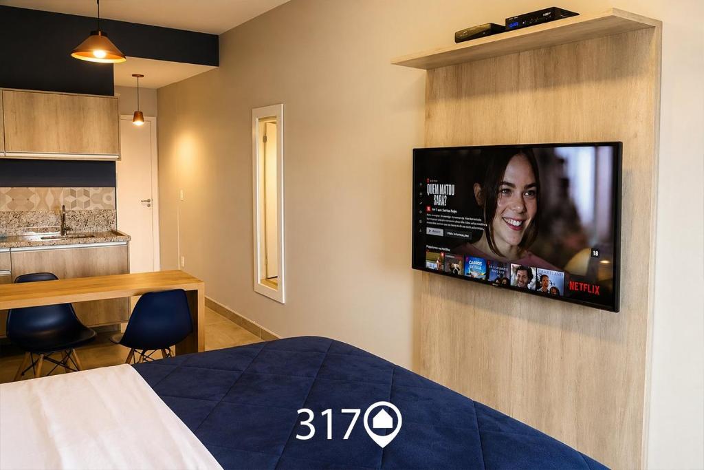 a bedroom with a flat screen tv on a wall at Studio com Garagem e Acessibilidade | Granja Viana in Taboão da Serra
