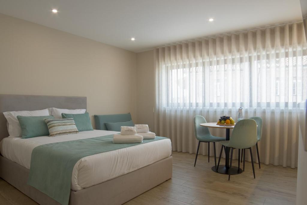 a bedroom with a bed and a table and chairs at Calvário Suites III in Chaves