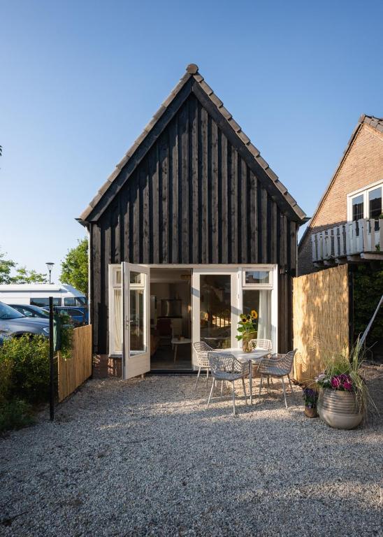 a large black barn with a table and chairs at Kortbie Zee in Biggekerke