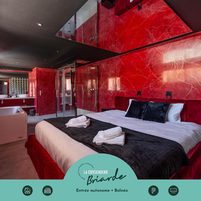 a bedroom with a large bed with a red wall at L'Interdit, Confort et Sensualité in La Ferté-Gaucher